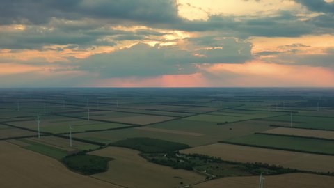 Aerial video of a wind turbines during sunset and stormy clouds
