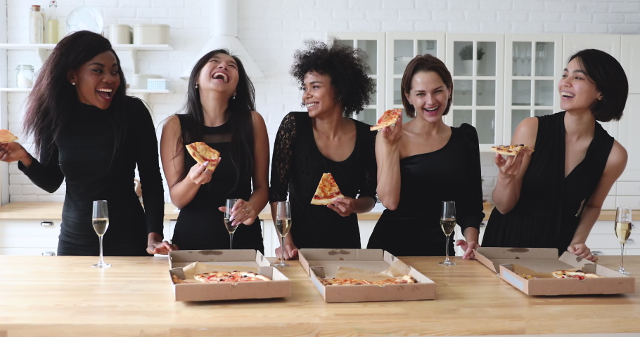 Happy cheerful funny attractive diverse young women best friends wear elegant black dresses drink champagne laugh share eat takeaway pizza together in kitchen celebrate hen sorority party together Royalty-Free Stock Footage #1041161704