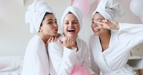 Cheerful beautiful korean and caucasian young girls best friends wear dressing gowns towels on head laughing look at camera, three happy diverse playful ladies gather on hen spa pajama slumber party