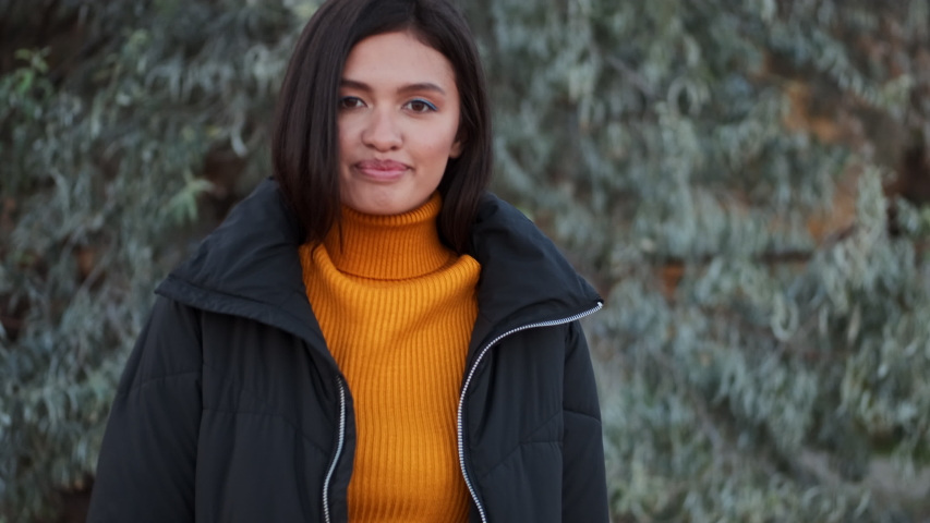 Attractive casual Asian girl in down jacket happily walking and whirling outdoor