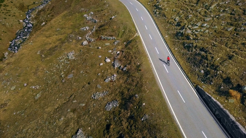 Cyclist in bright red jacket climbs up a beautiful mountain pass, enjoys scenery and views. Swiss alps travel destination for outdoor and sport lovers, top cycling spot for amateurs