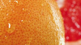 Slow motion video of water drops falling and rolling of fresh ripe orange peel. Perfect abstract shot for organic food and healthy nutrition. Closeup of citrus fruits