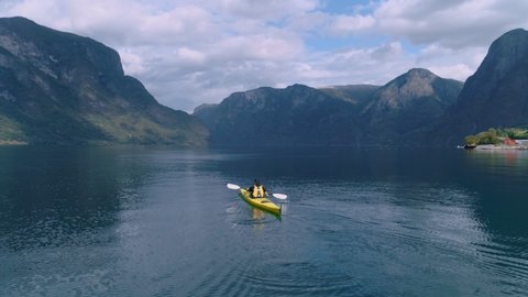 Drone shot of ambassador or travel blogger influencer paddle in middle of incredible and beautiful norwegian fjord in yellow kayak. Concept explore nature outdoors and digital nomad lifestyle choice