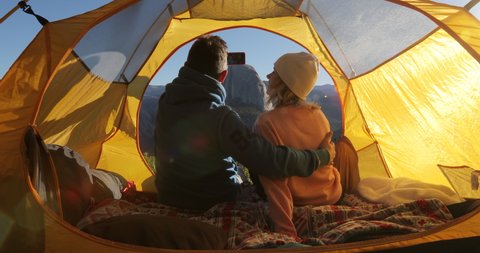 The view from the back on the couple sitting together in a tent and admiring the beauty of Yosemite Valley against the background of the central part of the Sierra Nevada ridge and Half Dome rock. 4k