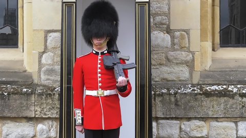 London, UK - April, 2019: British soldier transfers the gun from one hand to another. British guard in traditional red-black uniform on military duty. Front view, slow motion, video footage.