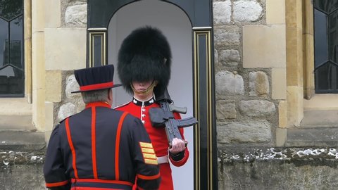 London, UK - April, 2019: Beefeater approaches the British soldier and gives instructions. British soldier guards the territory of the Tower of London. Yeoman Warders at the Tower of London.