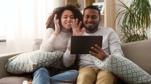 family, technology, communication and people concept - smiling happy african american couple with tablet pc computer having video call at home
