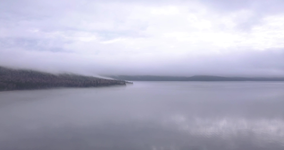 Drone shot of Lake and forest. Cloudy, hazy, blue, dark green, moody, mist, tree reflection, road, mysterious atmosphere. Lac Normand, Quebec, Canada, North America. Cold tones, amazing landscape.
