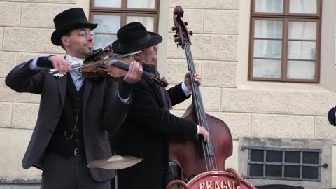 PRAGUE, CZECH REPUBLIC - OCTOBER, 2019.  Group of street musicians dressed in old-fashioned suits and hats play the violin, cello and accordion in tourist center of old city. Footage with Sound.