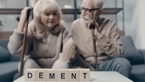 Senior couple putting word dementia on table