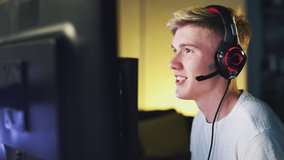 Excited Teenage Boy Wearing Headset Winning At Gaming At Home Using Dual Computer Screens