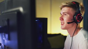 Excited Teenage Boy Wearing Headset Losing At Gaming At Home Using Dual Computer Screens