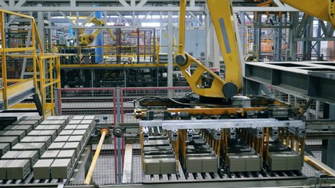 Modern factory machine carries bricks from a working conveyor.