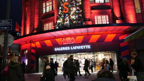 Strasbourg, France - Circa 2019: Tilt up over the large decorated facade of Galeries Lafayette department fashion store people locals and tourists walking in front during annual Christmas Market