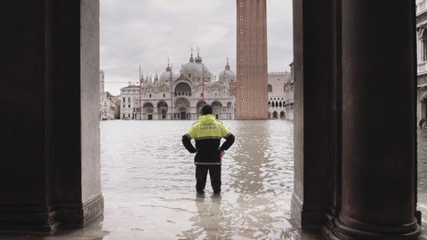 VENICE, ITALY - November 12, 2019: Police man doing surveillance on the St Mark square during the flood  (acqua alta) in Venice, Italy. Venice high water. 4k