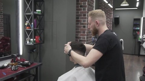 Minsk, Belarus 20.06.2019:
Barber cuts a man. Work in Barber shop. The barber is creating a new hair style for man.  The barber shaves a man. 