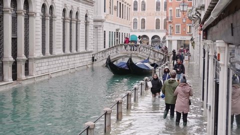 VENICE, ITALY - November 13, 2019: Tourists walking on the flooded sidewalks aside to the canal, Italy. 4k
