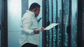 Frustrated angry black IT support technician arguing talking on headphones getting bad of difficult working tasks in server rack room. Data center. Stress work. - Powered by Shutterstock - Get 15% off with code: PIKWIZARD15