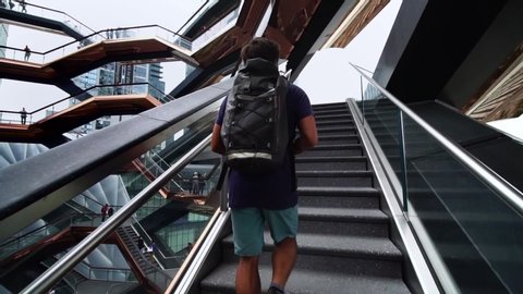 NEW YORK CITY, USA - OCT 27, 2019: Young backpacker traveler walking stairs in Vessel Hudson Yards in NYC. Concept of urban tourism, New York travel, landmark in Manhattan.
