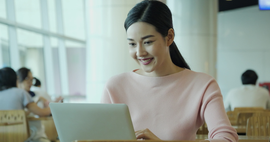 Beautiful asian woman using laptop to work at outdoor place. She looking to computer with attractive smile. | Shutterstock HD Video #1041242668
