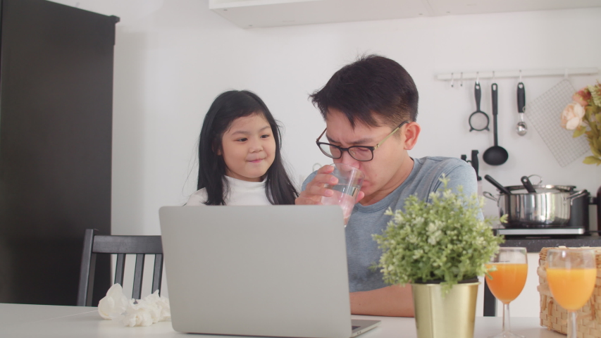 Young Asian businessman serious, stress, tired and sick while working on laptop at home. Young daughter consoling her father who working hard in modern kitchen at house in the morning concept. | Shutterstock HD Video #1041245698