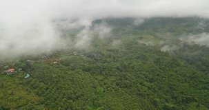 Aerial, drone, cloudy, haze, mist over mountain village, houses. Jungle, rainforest, agricultural, secluded, amazing beautiful scenic countryside. Phayao, nan province, thailand, south-east asia.