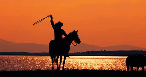 Silhouette  of Cowboy on horseback,Cowboy riding horse with beautiful sunset background and lake, horse with sunset landscape background,( life style)