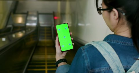 asian young woman use 5g full display smartphone on the escalator