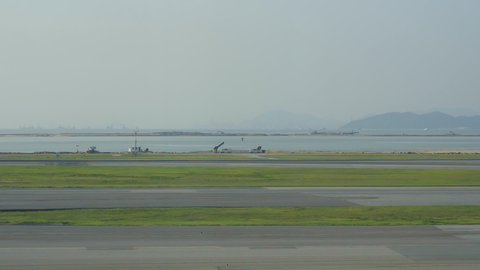 Hongkong, China - August 2019: Plane Qantas Australia moving along runway on background of beautiful nature landscape in city. White airplane running on airfield, landing in asian town with mountains
