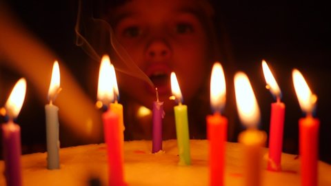 Cute little kid girl enjoy blow out candles on birthday cake celebrating at home slow motion