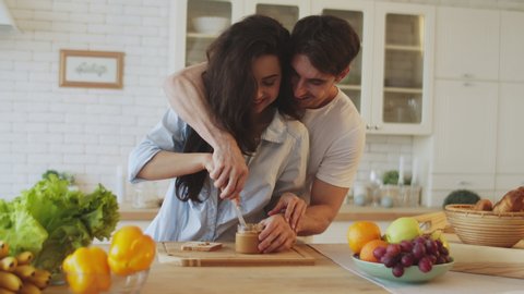Portrait of happy couple cooking together at home. Young married couple flirting at home kitchen. Sexy man and woman cooking breakfast at modern apartment.