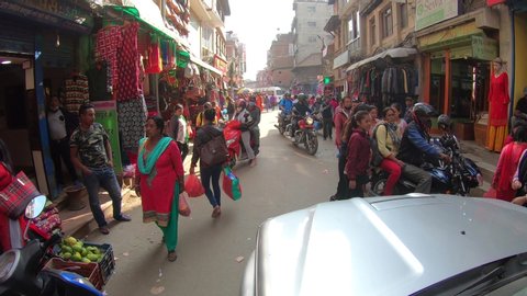 KATHMANDU, NEPAL - OCTOBER 24th, 2019. Typical colorful street scene in Kathmandu, Nepal, crowded by people, motorcycles and cars hard passing. Tourist area with shops selling gears and souvenirs
