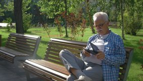 An elderly man with glasses reading an e-book on a Park bench - Powered by Shutterstock - Get 15% off with code: PIKWIZARD15