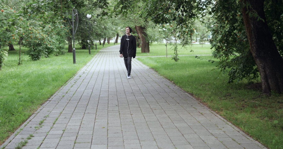 Happy young man listens to music from cassette player and moves to the beat outdoors. Slow motion - 60 fps.