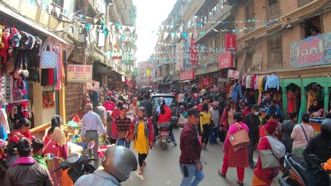 KATHMANDU, NEPAL - OCTOBER 24th, 2019. Typical colorful street scene in Kathmandu, Nepal, crowded by people, motorcycles and cars hard passing time lapse. Shops selling outdoor gears and souvenirs
