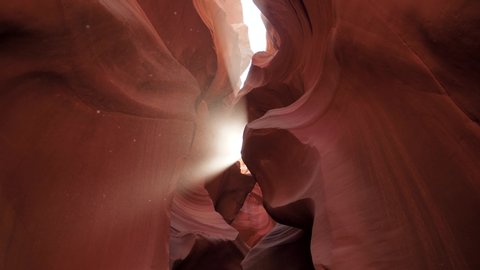 Antelope canyon with smooth and wavy sandstone walls red colors. Rock curves for photography and amazing slot canyon in Arizona USA, no people. Beam of sun shines through rock visible illuminated dust