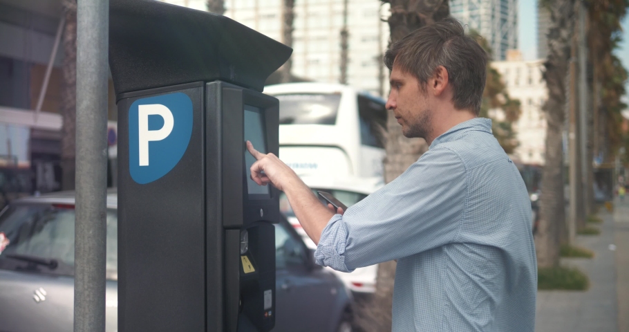 man inserting a parking lot ticket at an automated pay machine pay with card. Cash Automated machines parking lot in city attendants.