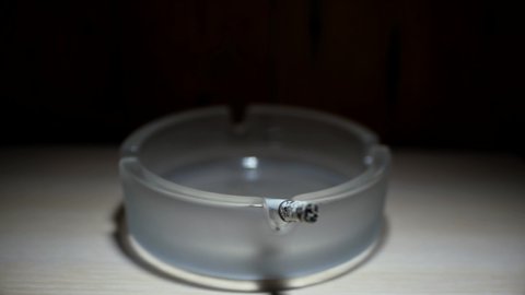 A cigarette smolders in an ashtray. Time lapse.