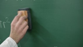 Teacher cleaning the chalkboard with maths equations .  - Powered by Shutterstock - Get 15% off with code: PIKWIZARD15