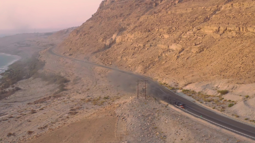 Car on fire with heavy smoke in the middle of the a mountain road, 4k aerial drone view