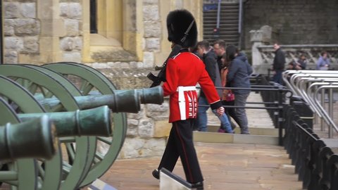 London, UK - April, 2019: British soldier in red uniform marches on duty along artillery cannons and stops near his post. British soldier bypasses the territory. Super slow motion, video footage.