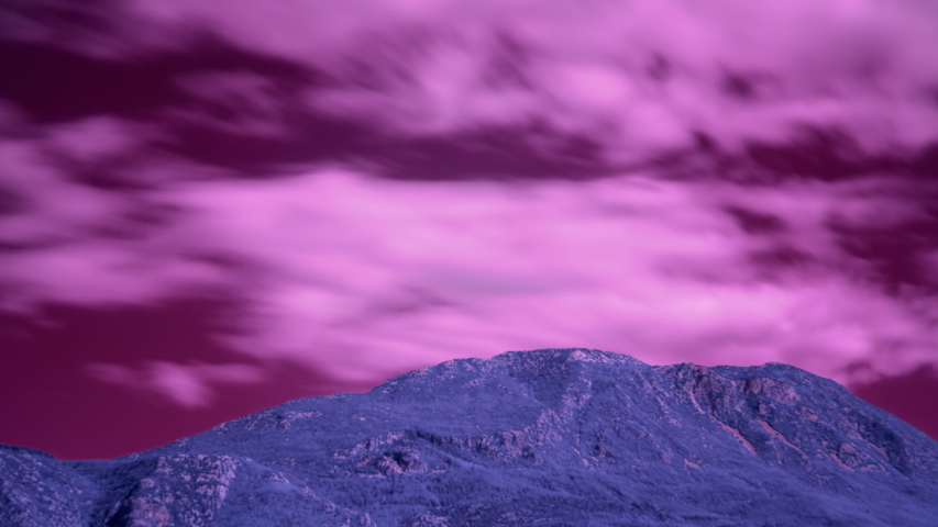 Alien landscape with mountain and long exposure clouds moving over it.