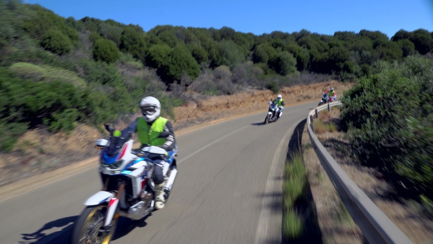 Motorcyclists drive fast along a country asphalt road with the ocean or sea in the background. POV Friends ride a motorcycle. Riding fun on an empty mountain landscape road while riding a motorcycle. 