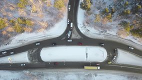 Aerial top-down view on winter road circle junction in pine forest under the snow. Cars and traffic on the highway. Static video, camera pinted down. Siberia, Russia