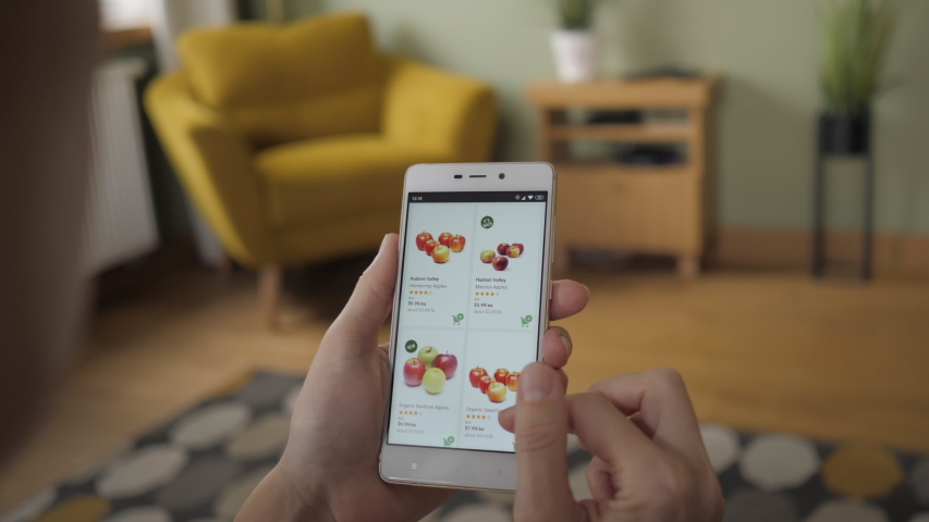 Woman Orders Food Home In An Online Store Using a Smartphone. Female Selects Fruit Apples in Grocery Online Store. Woman at Home Lying on Couch in Living Room Smartphone LOS ANGELES - October 2019 | Shutterstock HD Video #1041318262