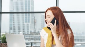 Joyful redhead girl beauty blogger working in office uses laptop and smartphone