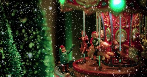 Close-up view of a christmas & event concept of a christmas toy village scene under the snow with a carousel toy full of lights. Perfect decoration for store for children at christmas