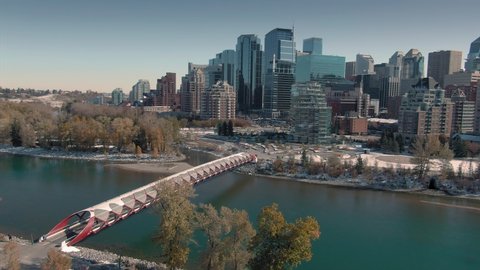 Aerial: Establishing shot of the Calgary city skyline. In the foreground is the Peace Bridge & the Bow River 