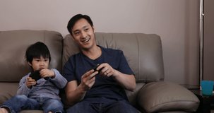 Front view close up of a Chinese Asian man and his young son in their living room, in their
