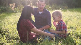 happy family teamwork outdoors concept outdoors slow motion video. mom dad and son in nature are sitting on the grass have fun playing. mom lifestyle girl dad man and son boy happy family